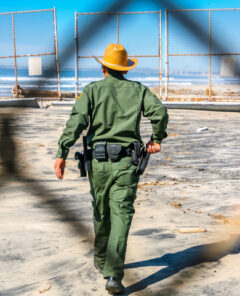 Tijuana, Mexico, Feb 14 - An agent of the US Border Patrol inspects the steel wall on the border between the United States and Mexico build on the Pacific coast of Tijuana. In the background the Imperial Beach in US territory and the San Diego city skyline.