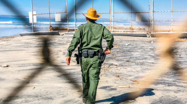 Tijuana, Mexico, Feb 14 - An agent of the US Border Patrol inspects the steel wall on the border between the United States and Mexico build on the Pacific coast of Tijuana. In the background the Imperial Beach in US territory and the San Diego city skyline.